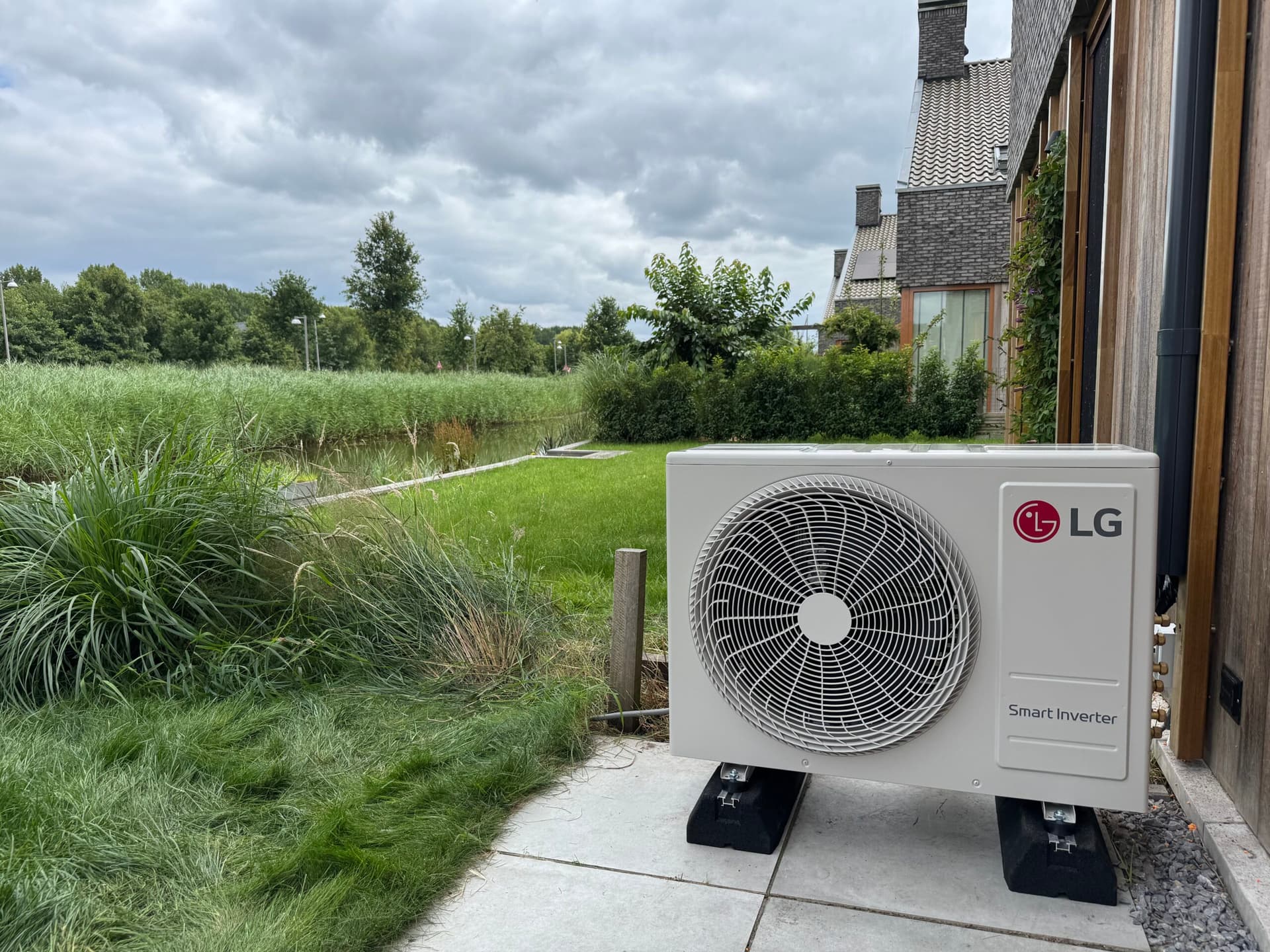 LG airco buitenunit geïnstalleerd tegen de gevel van een woning met tuin